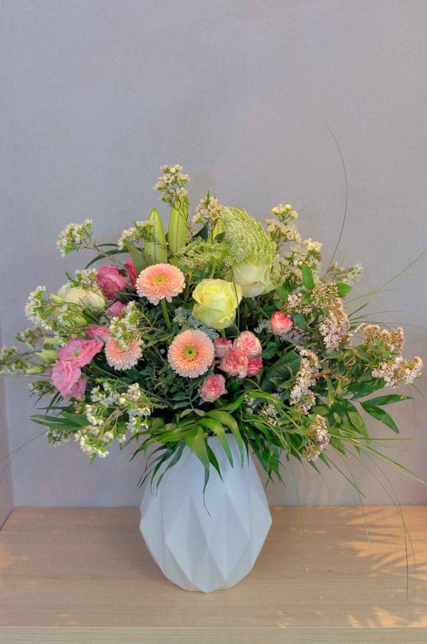Bouquet rond de fleurs pastel dans un vase en céramique style Origami
