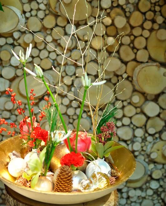Composition de Noël avec une assiette creuse de couleur or et de boules dont des fleurs